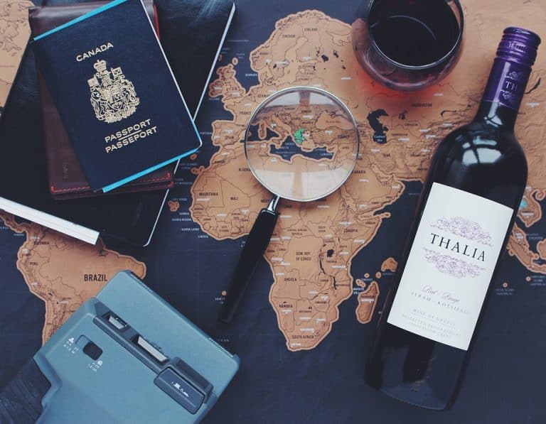 An image of a world map with a passport, magnifying glass, and other travel materials on top of it.