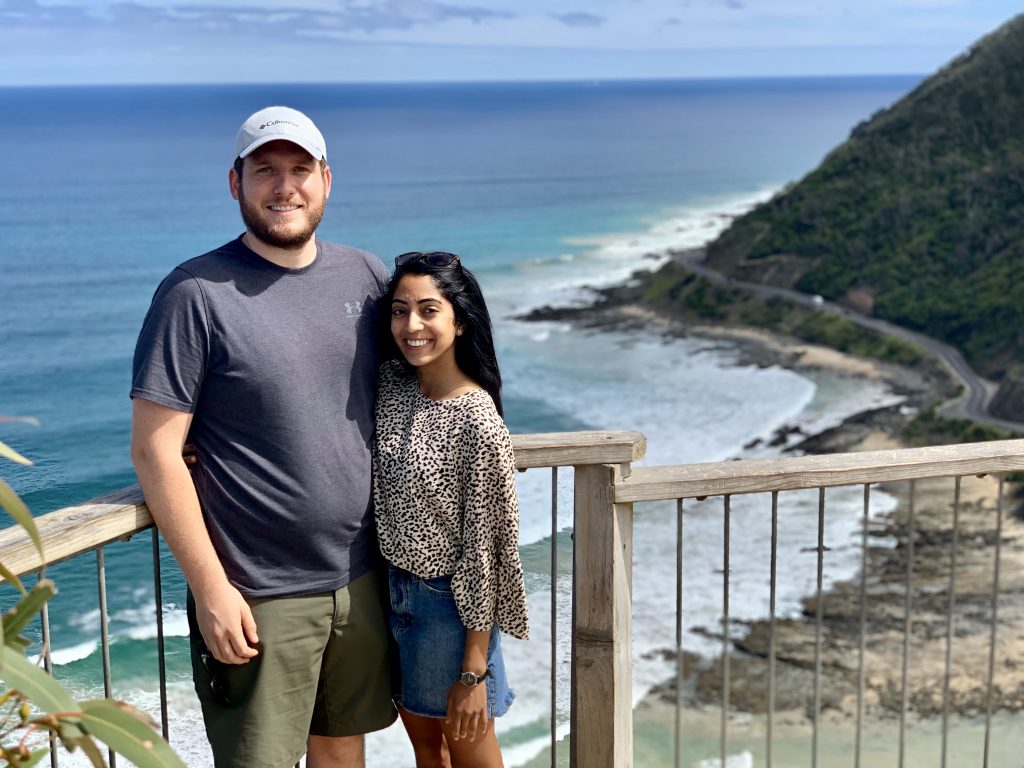 a picture of me and my husband overlooking the ocean while standing on a cliff in australia