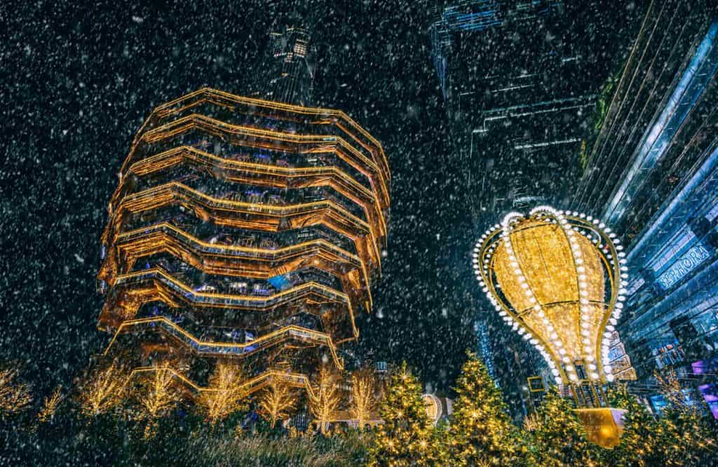 Lit up Vessel and balloon at Hudson Yards at night.