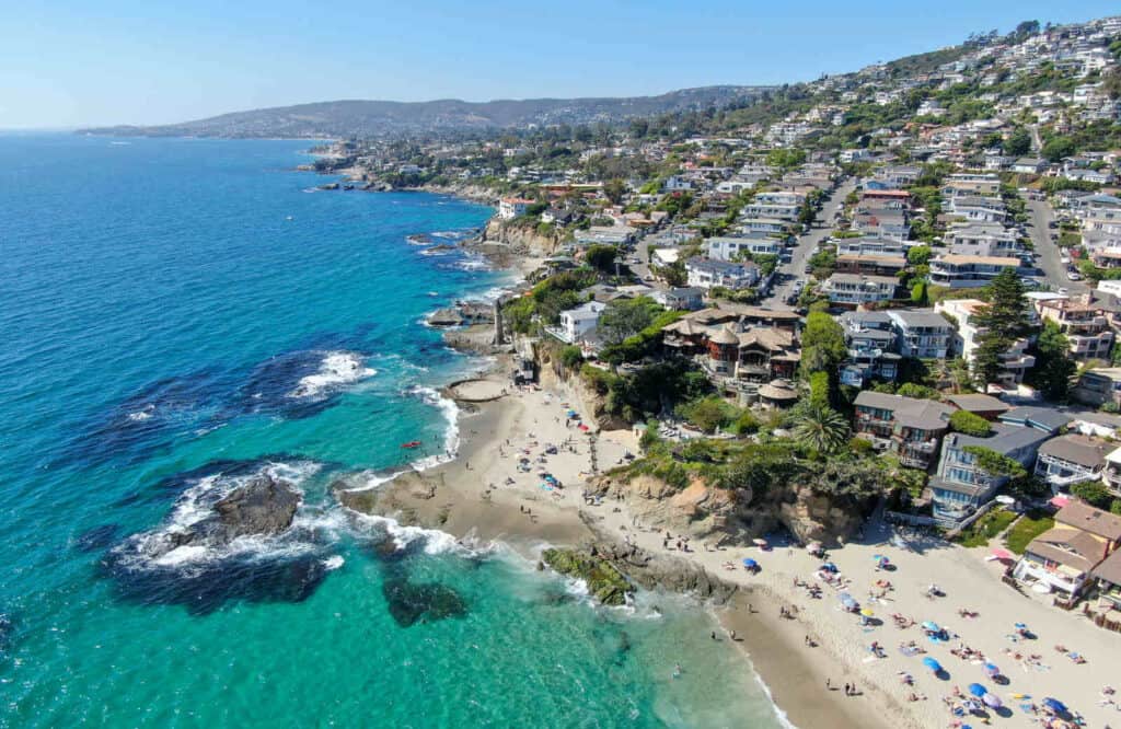 Aerial view of the coastline of Laguna Beach with its turquoise water and brown sand.