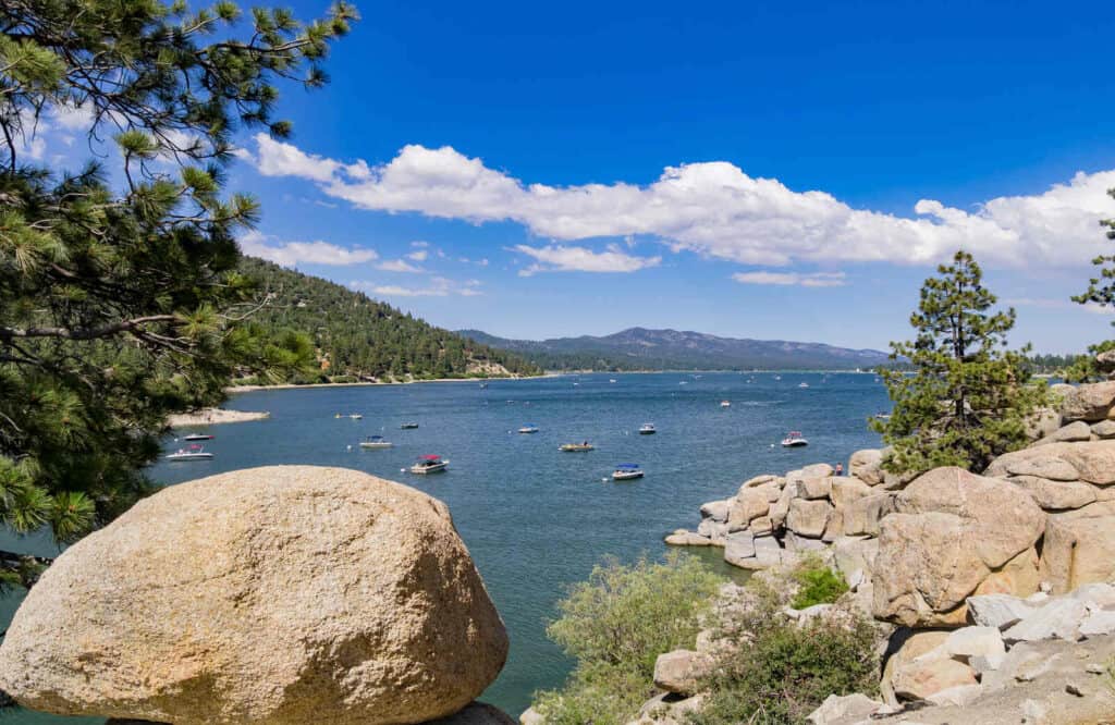 Aerial view of a few boats on Big Bear Lake surrounded by trees and mountains.