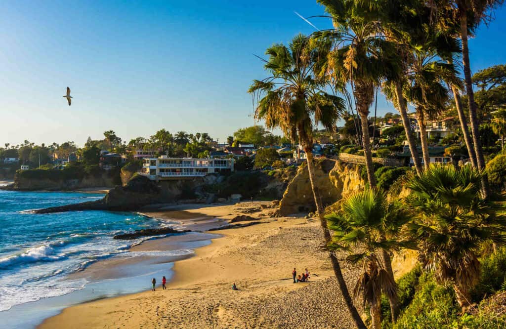Heisler Park in Laguna Beach with golden sand, palm trees, and a house on the beach.