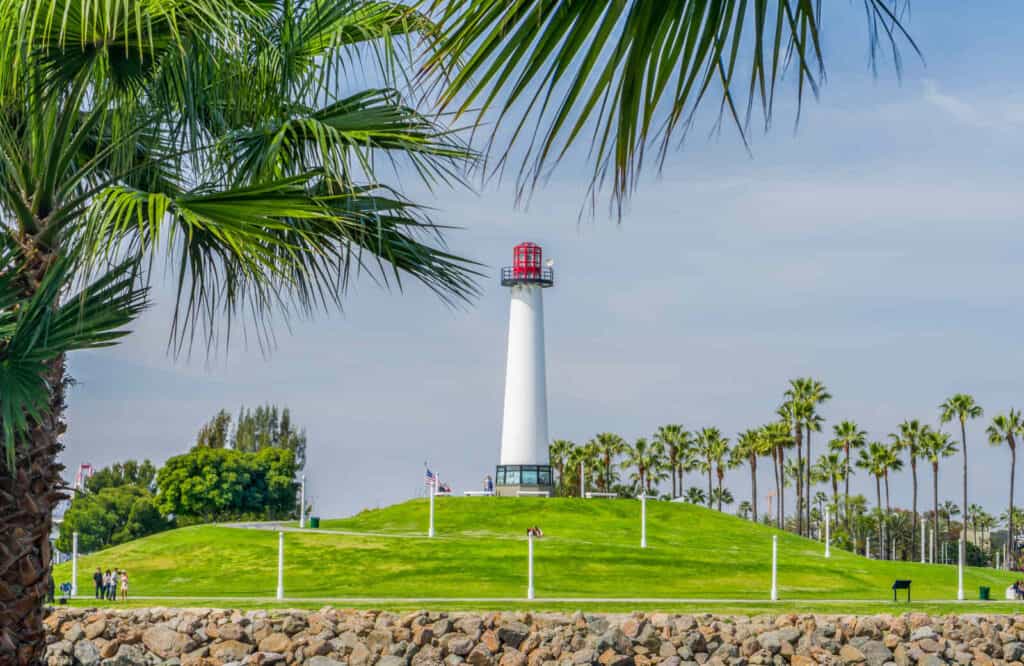 Towering white lighthouse perched on a small hill, which is Lions Lighthouse in Long Beach.