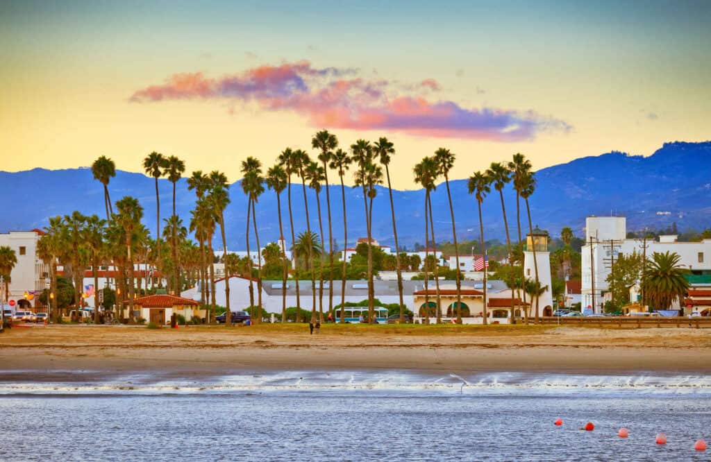 View of the Santa Barbara coastline from the pier with golden sand and tall palm trees.