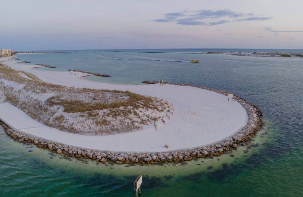 Aerial view of a curve around Norriego Point Beach with powdery white sand and clear emerald waters.